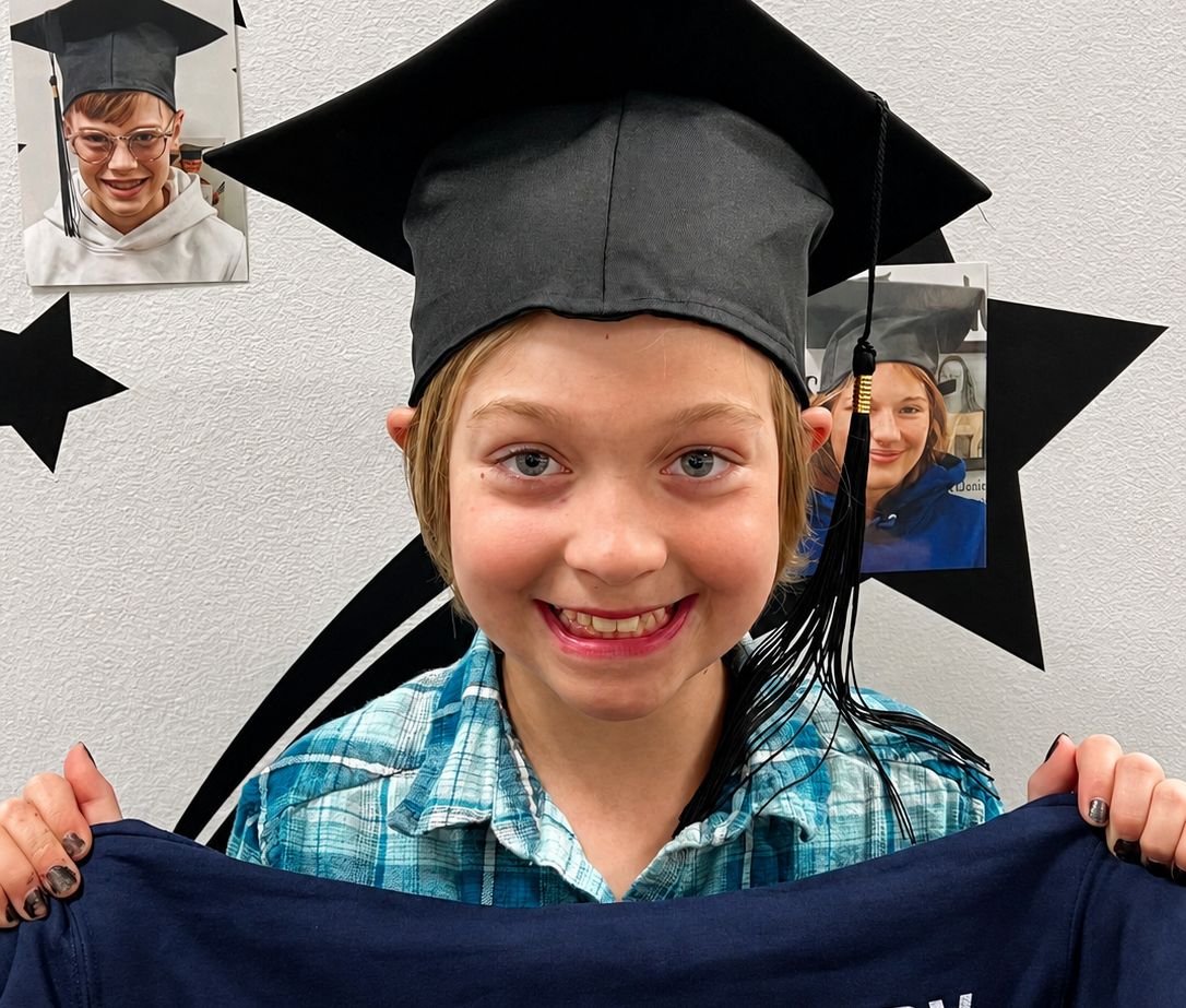 A smiling young patient in a graduation cap celebrating finishing vision therapy at Webb Eyecare.