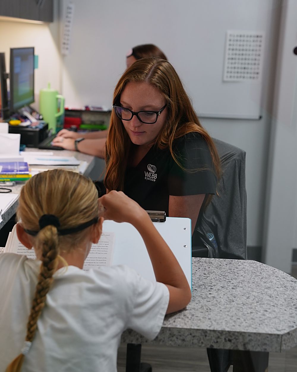 A Webb Eyecare vision therapist working through a reading exercise with a young patient.